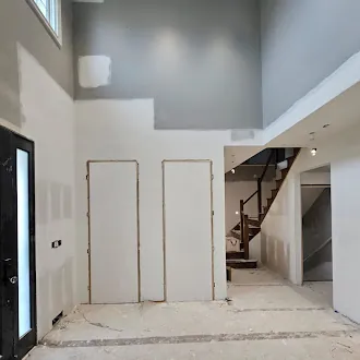 Entrance before — bare drywall and unfinished stairs during construction